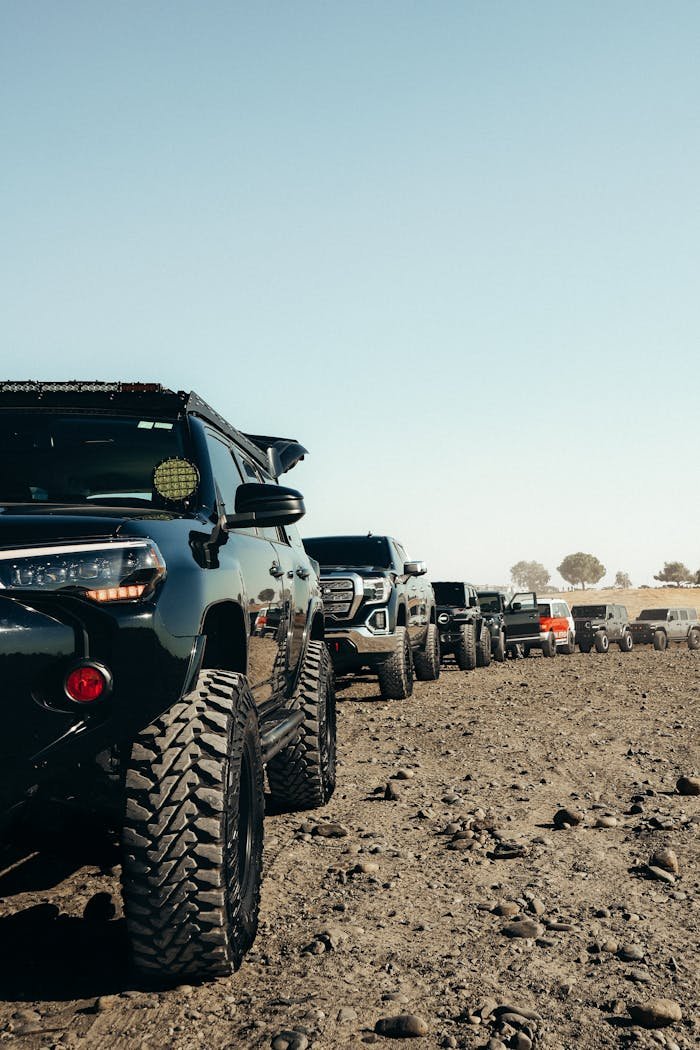 why-choose-us Offroad vehicles lined up on rugged, rocky terrain under a clear blue sky.