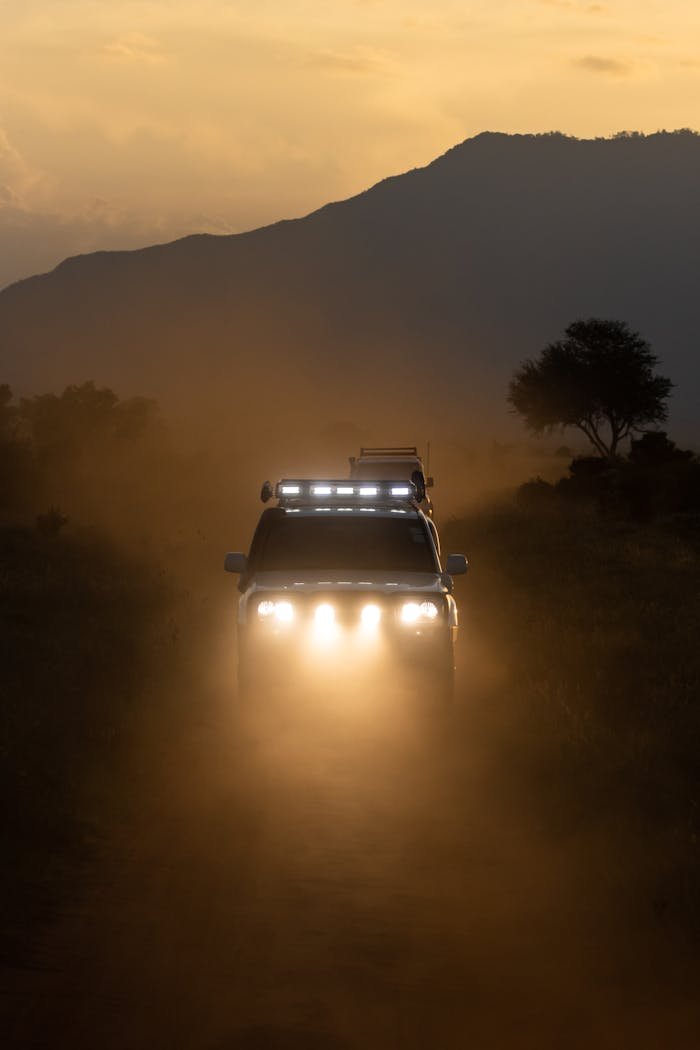 Services-01 An off-road SUV drives through the dusty savannah of Tsavo, Kenya at sunset.